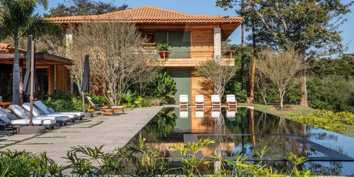 Casa a beira de lago na Quinta da Baroneza integra novos volumes à paisagem do campo