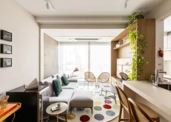 Neste living assinado pela arquiteta Elisa Maretti, o tapete de cores vibrantes assume o protagonismo. Com formato circular, ele contrasta com as linhas retas do ambiente, adicionando leveza, movimento e um toque de descontração ao espaço | Foto: Manuel Sá