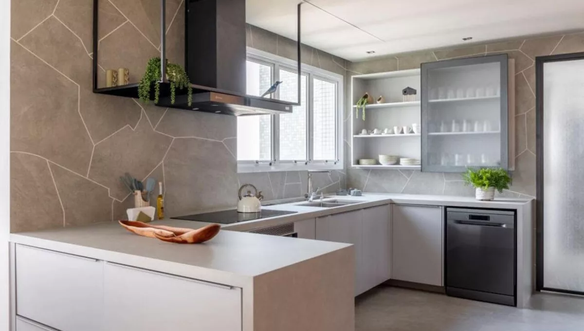 No projeto dessa cozinha, o arquiteto Raphael Wittmann adornou as paredes com o mesmo porcelanato do piso, mas de uma outra maneira: ousou a produzir recortes orgânicos, realizados na obra, para entregar um toque moderno e natural ao ambiente | Projeto Rawi Arquitetura + Design | Foto: Rafael Renzo