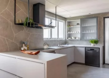 No projeto dessa cozinha, o arquiteto Raphael Wittmann adornou as paredes com o mesmo porcelanato do piso, mas de uma outra maneira: ousou a produzir recortes orgânicos, realizados na obra, para entregar um toque moderno e natural ao ambiente | Projeto Rawi Arquitetura + Design | Foto: Rafael Renzo