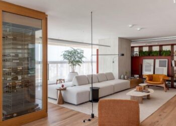 Batizado de ‘Apartamento Ripas’, o projeto do arquiteto Raphael Wittmann exibe uma área de estar grandiosa que reflete a identidade dos moradores. Uma adega entrega imponência logo na entrada e possui duas portas que servem ao estar e à sala de jantar | Projeto Rawi Arquitetura + Design | Foto: Rafael Renzo