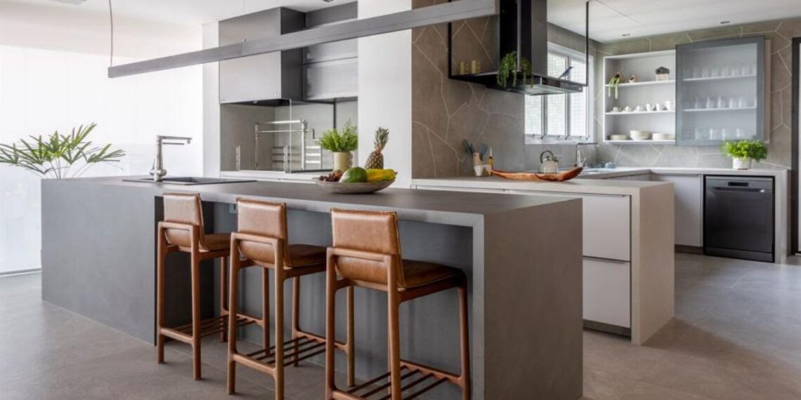 Nesse projeto realizado pelo arquiteto Raphael Wittmann, a bancada, executada em lâmina ultracompacta, atende a cozinha como espaço para as refeições, além de estender-se para a área gourmet. Para os assentos, três charmosas banquetas Ada, em couro, assinadas pelo Estudiobola | Projeto Rawi Arquitetura + Design | Foto: Rafael Renzo